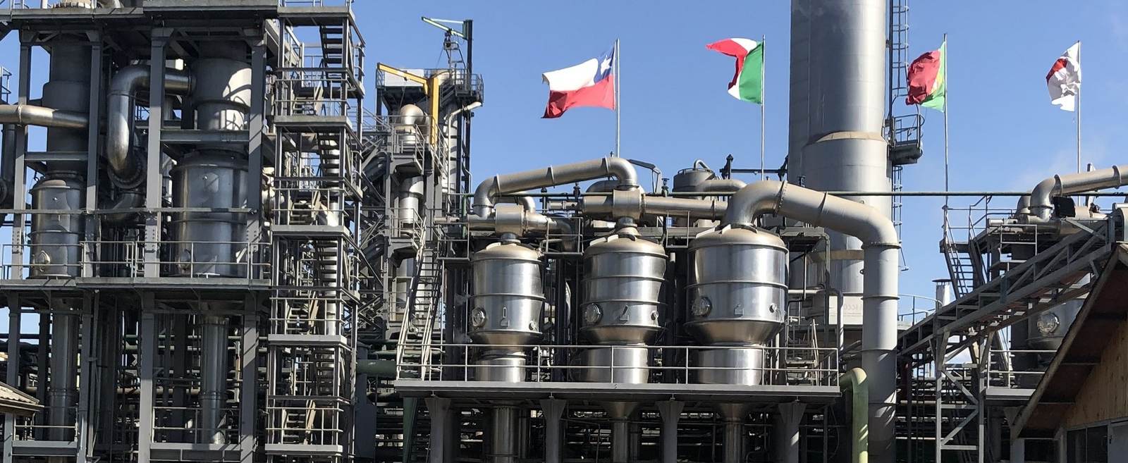 Planta industrial de processamento de ingredientes, com evaporadores e tubulação em aço inox.